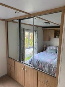 1 dormitorio con cama y espejo grande en Lili-anns Retreat Cosy Holiday Home en Millom