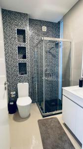 a bathroom with a toilet and a glass shower at Duarte Apartments - Morabeza in Mindelo