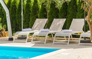 a group of three lounge chairs next to a pool at APP Laura with Common Pool in Nova Vas