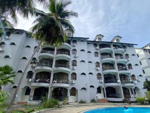 a large white building with a palm tree in front of it at Adiana Homestay in Kuah