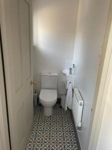 a bathroom with a white toilet and a tile floor at Rosedene Regency Annex in Minster