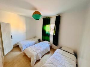 um quarto com três camas e um lustre em Cozy Surf House em Taghazout