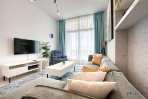 a living room with a couch and a tv at Contemporary 1BR at Prime Views Meydan by Deluxe Holiday Homes in Dubai