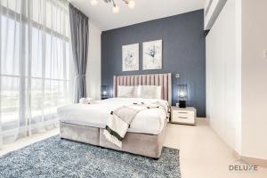 a bedroom with a large bed and a blue wall at Contemporary 1BR at Prime Views Meydan by Deluxe Holiday Homes in Dubai
