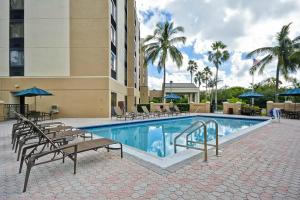 una piscina en un hotel con sillas y sombrillas en Hyatt Place Miami Airport-West/Doral, en Miami