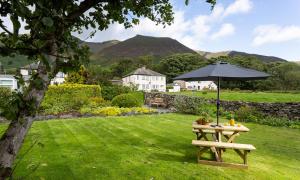 a picnic table with an umbrella in the grass at Blease Garth in Threlkeld