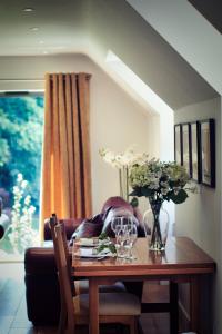 a dining room table with flowers and a couch at The Loft at Hewletts Farm - Stunning Apartment on The Cotswold Way Close to Cheltenham in Cheltenham