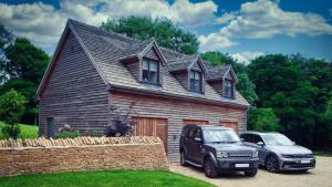 two cars parked in front of a wooden house at The Loft at Hewletts Farm - Stunning Apartment on The Cotswold Way Close to Cheltenham in Cheltenham