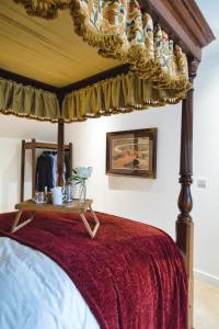 ein Schlafzimmer mit einem Himmelbett und einer roten Tagesdecke in der Unterkunft The Loft at Hewletts Farm - Stunning Apartment on The Cotswold Way Close to Cheltenham in Cheltenham