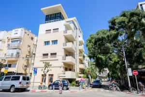 un edificio blanco alto con coches estacionados frente a él en Central 2BR in Ben Yehuda by Holiday-rentals, en Tel Aviv