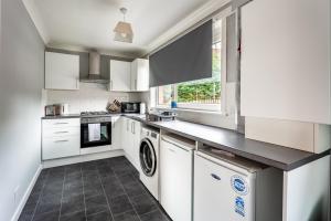 a kitchen with white cabinets and a dishwasher at Scotia House -3 bed house in Larkhall with private driveway in Larkhall