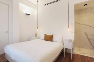 biała sypialnia z białym łóżkiem i ścianą w obiekcie Modern 1BR in Dizengoff by Holiday-rentals w Tel Awiwie