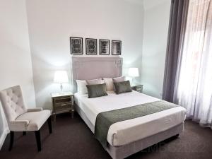 een slaapkamer met een groot wit bed en een stoel bij Mansions on Pulteney in Adelaide