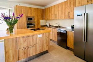 cocina con armarios de madera y nevera de acero inoxidable en Villa La Roca en Torreguadiaro