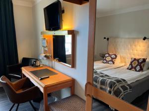 a hotel room with a bed and a desk and a mirror at Hotell Östermalm in Motala