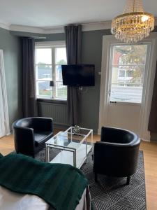 a living room with two chairs a table and a tv at Hotell Östermalm in Motala