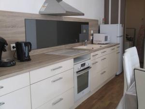 a kitchen with white cabinets and a sink and a refrigerator at La p'tite maison du Chateau in Éclassan