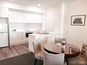 een keuken met een tafel en stoelen en een koelkast bij Mansions on Pulteney in Adelaide