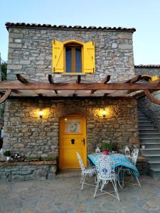 stół i krzesła przed budynkiem z żółtymi drzwiami w obiekcie Ilios Guest House w mieście Gokceada