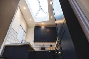 a kitchen with black cabinets and a skylight at Cathys Cottage, Sun Trap Patio, Modern 3 Bed, Central, Parking in Crewkerne +29 photos