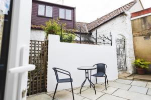 a patio with two chairs and a table on a white wall at Cathys Cottage, Sun Trap Patio, Modern 3 Bed, Central, Parking in Crewkerne
