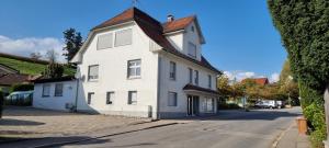 a white house with a red roof on a street at 2 Zimmerwohnung in 88099 Neukirch ab 2 Übernachtungen in Neukirch