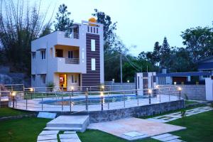 a large house with a swimming pool in front of it at The green pride resort in Yelagiri