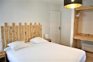 Schlafzimmer mit einem weißen Bett mit einem Kopfteil aus Holz in der Unterkunft 5 mn Zenith Grande Halle Auvergne,pied de Gergovie,Garage,Netflix in Romagnat