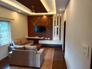 a living room with a couch and a tv at The green pride resort in Yelagiri