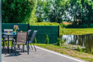 a table and chairs sitting next to a pond at Hygge Domki in Junoszyno +36 photos
