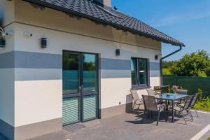 a patio with a table and chairs in front of a house at Hygge Domki in Junoszyno