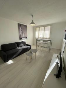 ein Wohnzimmer mit einem schwarzen Sofa und einem Tisch in der Unterkunft Charmant Appart Stade Vélodrome/Métro Centre Ville in Marseille