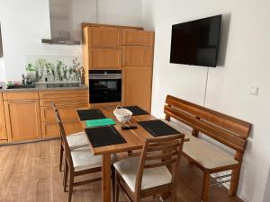 a kitchen with a wooden table with chairs and a television at Schiller Apartment in Münchberg