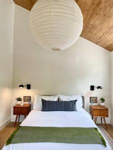 a bedroom with a large white bed and a large light fixture at The Cedar at Mira Riverfront Getaway in Marion Bridge