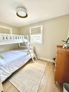 ein Schlafzimmer mit einem weißen Etagenbett und einem Teppich in der Unterkunft The Cedar at Mira Riverfront Getaway in Marion Bridge