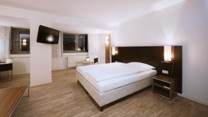 a bedroom with a white bed and a flat screen tv at Panorama Hotel Schweinfurt in Schweinfurt