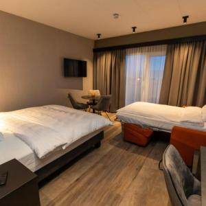 a hotel room with two beds and a table and chairs at Hotel Halond in Akureyri