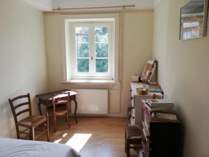 een slaapkamer met een tafel en een raam en een tafel en stoelen bij Le Grand Feuvrier in Dole