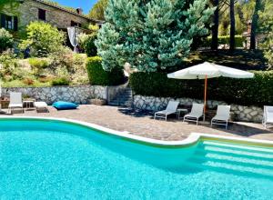 a swimming pool with chairs and an umbrella and an umbrella at La Panoramica Gubbio - Maison de Charme - Casette e appartamenti self catering per vacanze meravigliose! in Gubbio