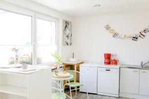 eine Küche mit weißen Schränken sowie einem Tisch und Stühlen in der Unterkunft Kleines Kunsthaus. in Nordhausen