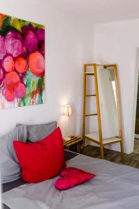 ein Schlafzimmer mit einem roten Kissen und einem Gemälde an der Wand in der Unterkunft Kleines Kunsthaus. in Nordhausen