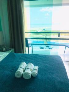 two rolled up towels on a bed with a view of the ocean at Pousada Dotô Sonhadô Beach in Ponta de Pedras