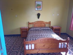 1 dormitorio con 1 cama de madera y 2 mesitas de noche en Suerte Loca, en Sidi Ifni