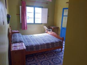 a small bedroom with a bed and a window at Suerte Loca in Sidi Ifni