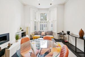 ロンドンにある1 & 2 Bed Cosy Apartments next to Earls Court FREE WIFIのリビングルーム(ガラスのテーブル、椅子付)