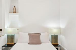 ロンドンにある1 & 2 Bed Cosy Apartments next to Earls Court FREE WIFIのベッドルーム1室(白いベッド1台、ランプ2つ付)