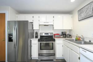 cocina con armarios blancos y nevera de acero inoxidable en Cozy Couve Apartment Close To Everything!, en Vancouver