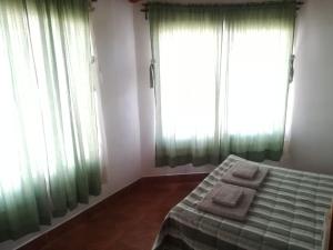 a bedroom with green curtains and a bed with towels on it at El Pesebre in Cachí