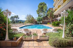 una piscina en un patio con sillas y un edificio en Can Fisa Hotel & Apartments en Corbera de Llobregat