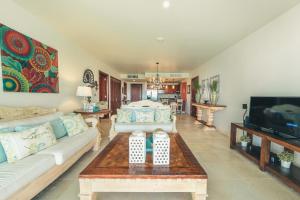 a living room with a couch and a tv at Punta Palmera Beachfront Apartment in Punta Cana